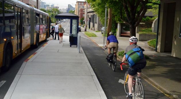 People biking by a bus stop